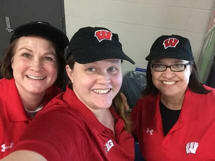 3 Women in badger shirts and hats at a concession stand